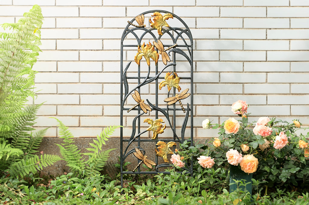 garden trellis with golden and white iris flowers and dragonfly motifs, placed in outdoor garden 