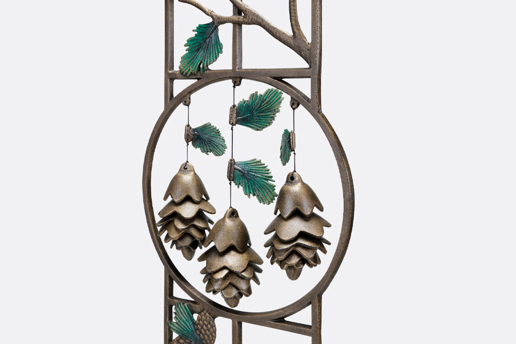 Close-up view of three pinecone shaped wind art pendants hung within a garden trellis