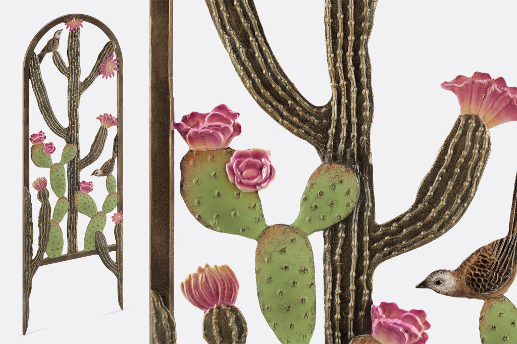 close-up view of sculpted cactus spines on the garden trellis; it features two cacti with pink blooms and cast metal birds