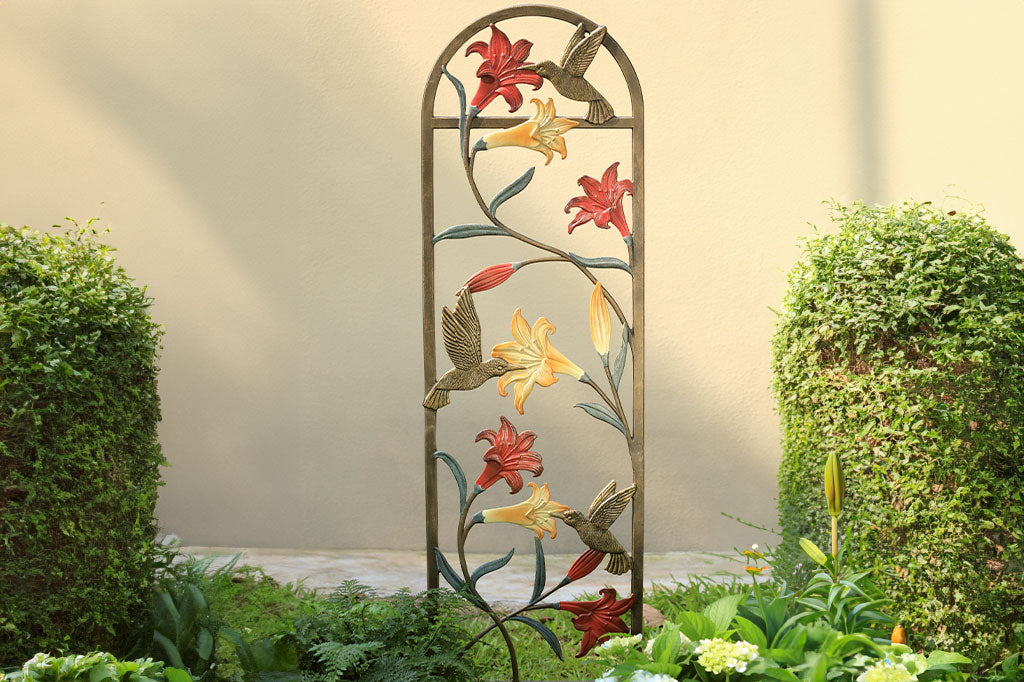 trellis shown in garden with coral and yellow lilies and a hummingbird motif