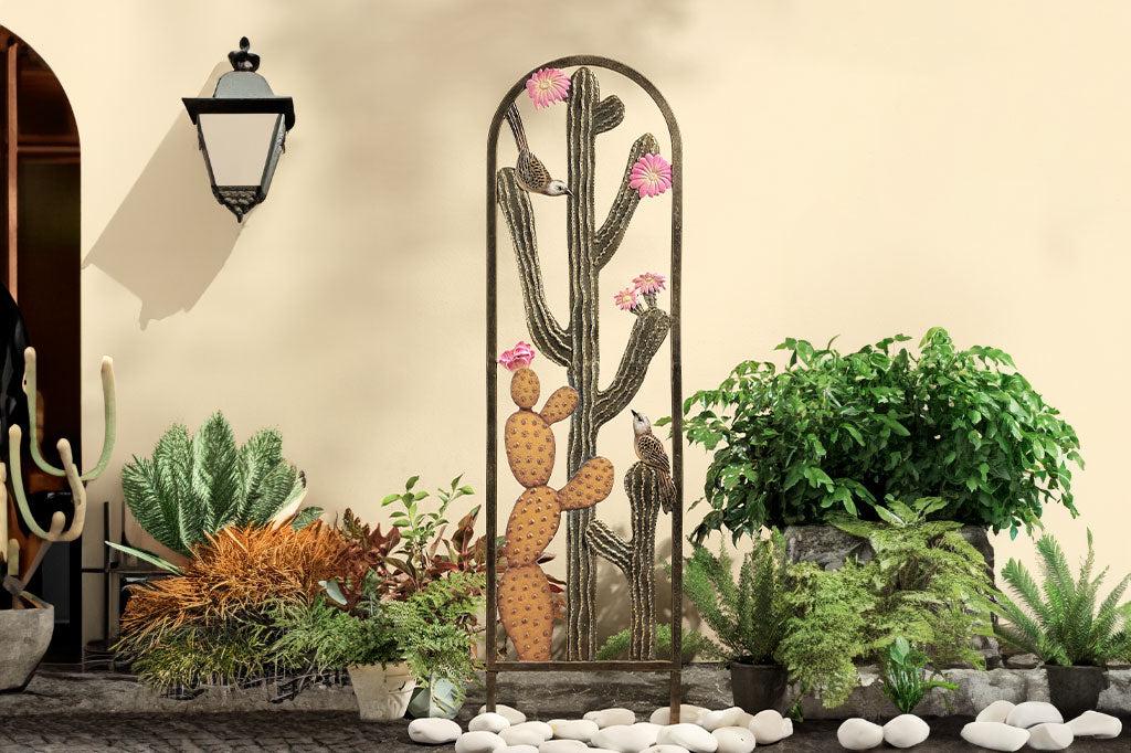 Cast metal trellis with cactus and blooms detailing shown outside a home with rock and palm garden