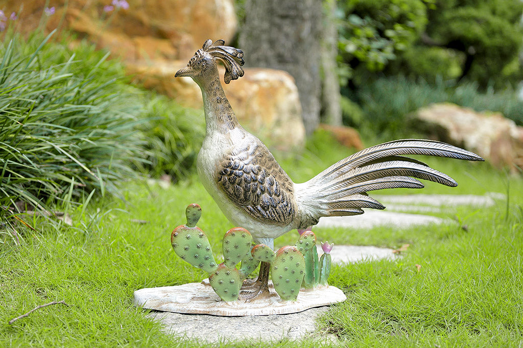 Road runner bird sculpture with sculpted cacti, on a grassy area in a garden
