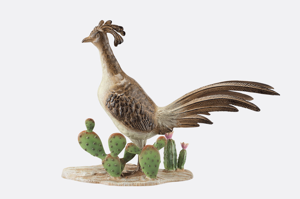 A statue of a roadrunner stood between a group of cacti.