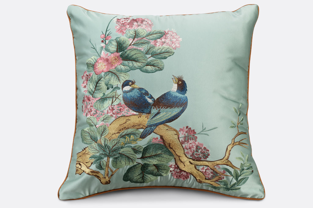 blue satin pillow, embroidered lovebirds seated on branch surrounded with leaves and blooms