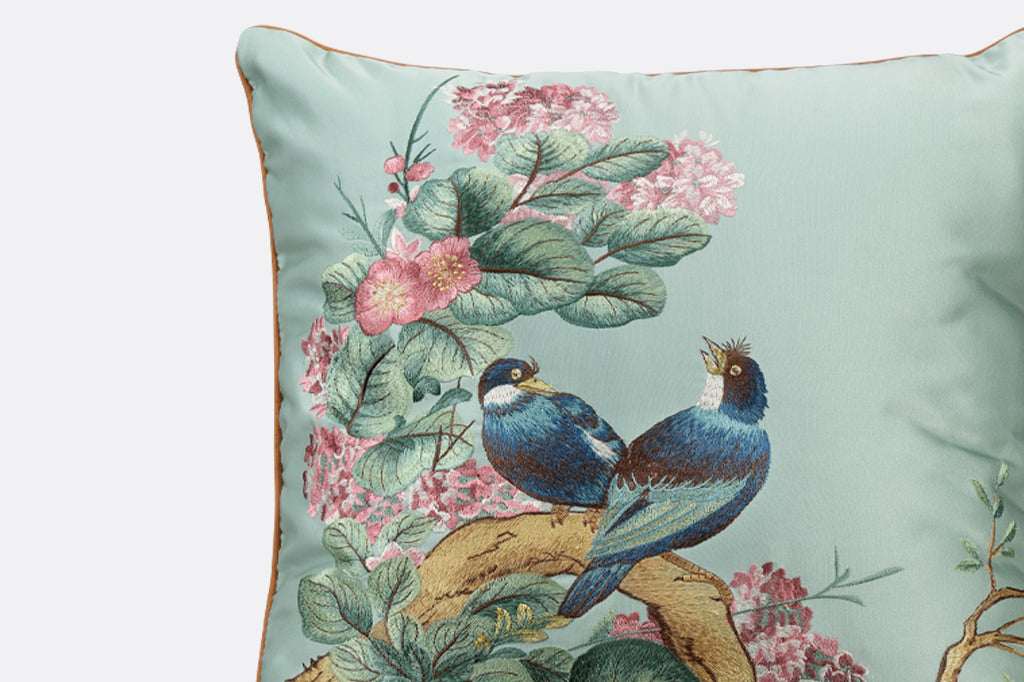 detailed view of embroidery, two dark blue love birds seated on branch with leaves and flowers 
