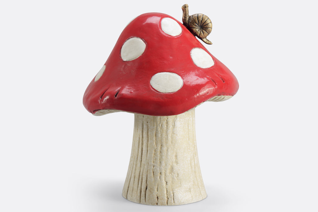 red mushroom garden sculpture with white spots and a bronze garden snail on mushroom cap. 