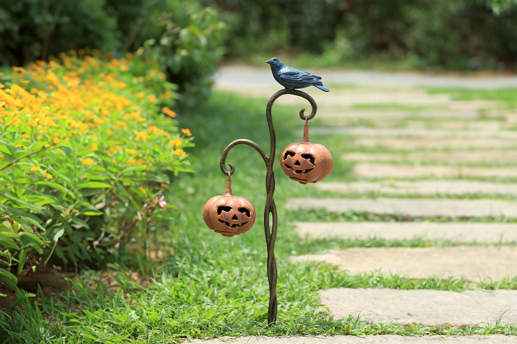 cast metal twisted branch lantern holding two jack o lantern lanterns with black blue raven sitting on branch 