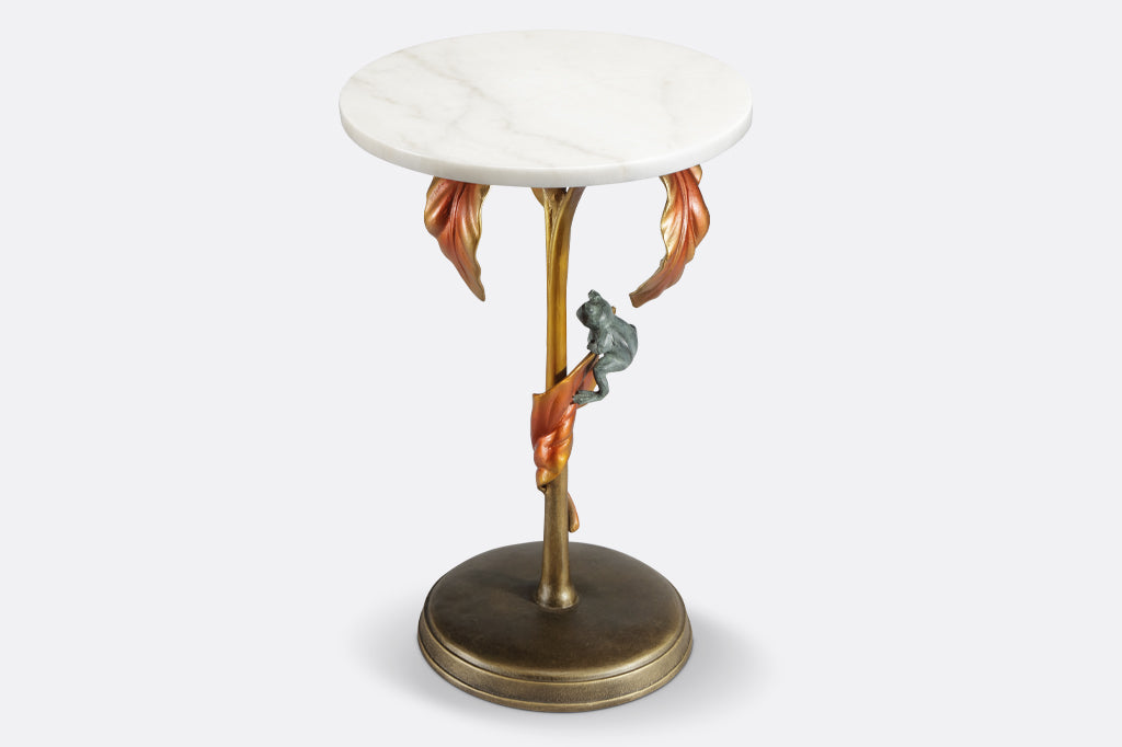 cast metal tropical drink table with white marble top in a coppery color featuring tropical leaves and a green frog balancing on a leaf 