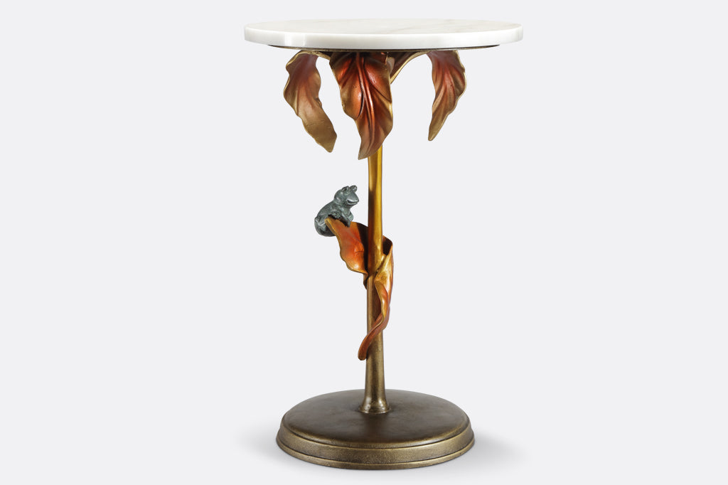 cast metal tropical drink table with white marble top in a coppery color featuring tropical leaves and a green frog balancing on a leaf 