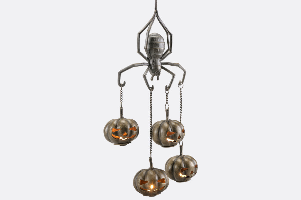 cast metal spider with four jack o lantern pumpkins suspended from spider arms, pumpkins alight 