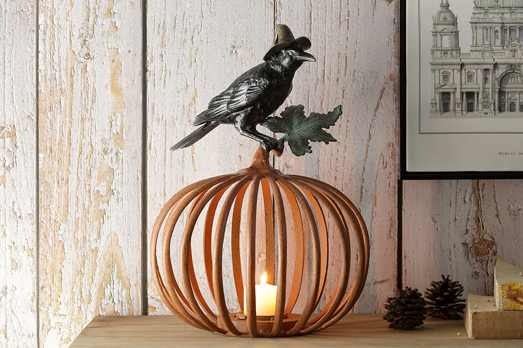 Cast metal orange pumpkin with black raven in witch hat sitting atop, candleholder