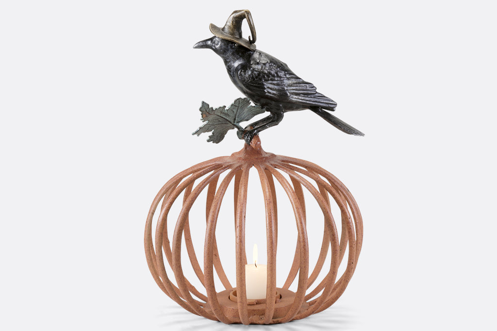 Cast metal orange pumpkin with black raven in witch hat sitting atop, candleholder