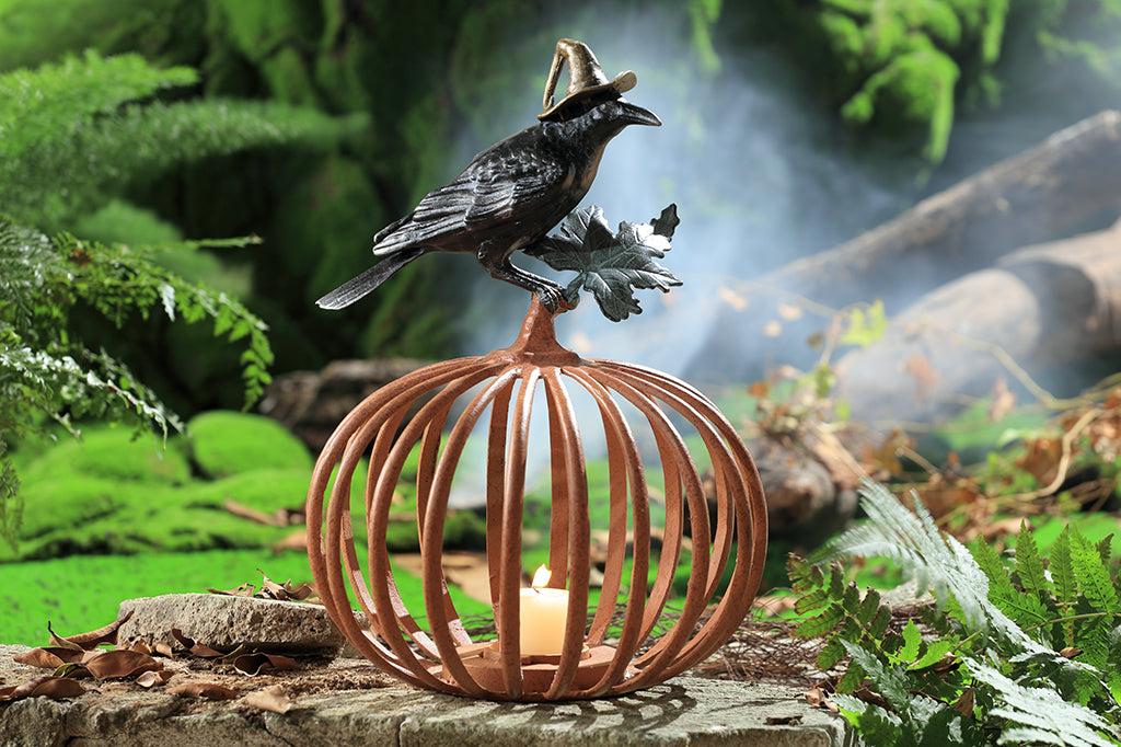 Cast metal orange pumpkin with black raven in witch hat sitting atop, candleholder