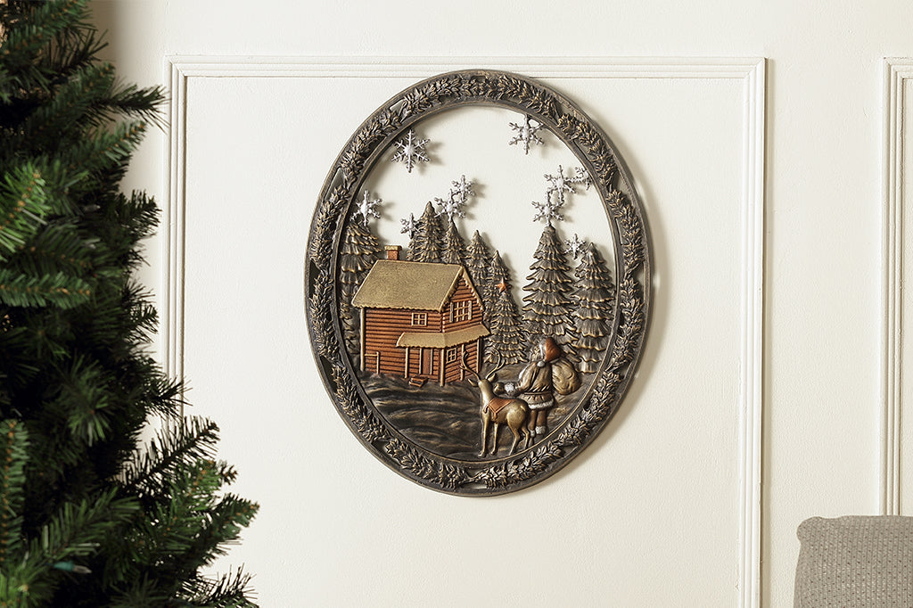 Cast metal circle wall art with pine trees, a cozy cabin, and santa with a present sack 