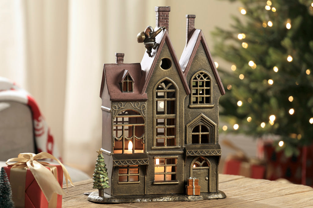 Up on the Rooftop Candle House candleholder with removeable santa, tree, and present accessories shown on table in home christmas scene with lit candles