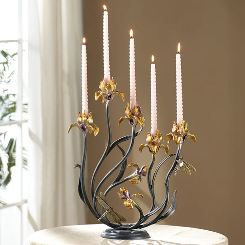 Decorative candle holder with floral design and lit candles on a neutral background