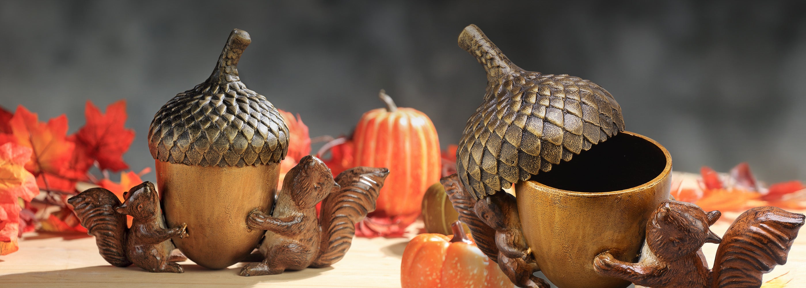 Decorative acorn and squirrel figurines with pumpkins on a blurred autumn background