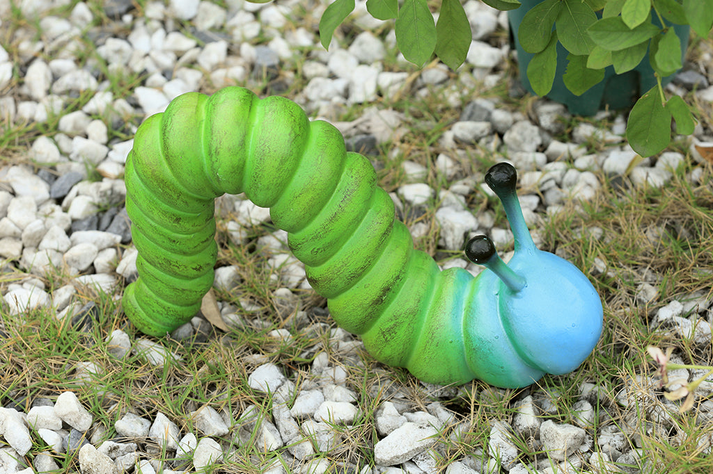 cast metal caterpillar with two antenna, colored in a lime green fading to a sky blue towards the head of caterpillar set in garden rock scene 