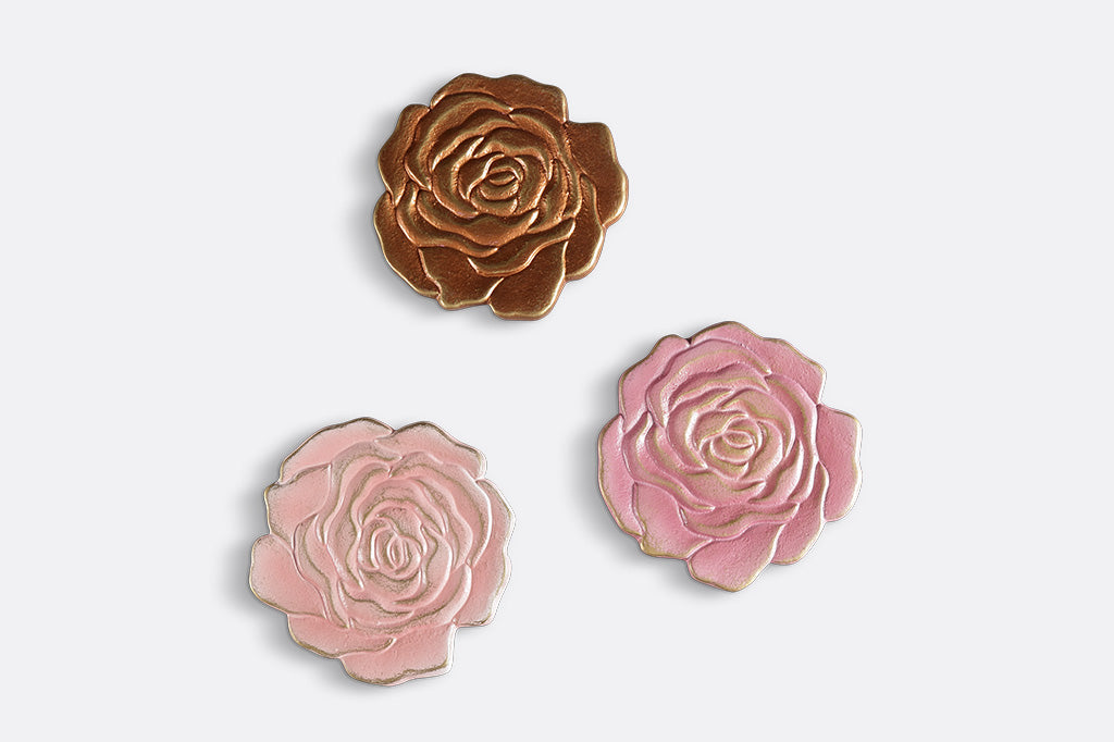 Three rose blossom coasters in shades of pink and copper, top view