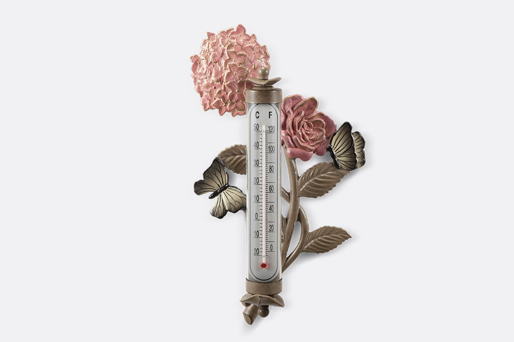 Wall mounted thermometer with cast metal accents of pink rose and hydrangea blossoms, butterflies, and leaves