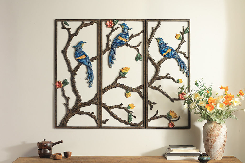 Decorative wall art with birds and branches on a wall above a wooden surface.