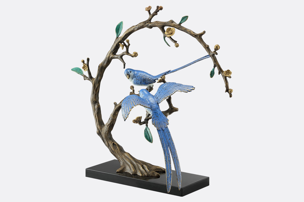 A statue of two blue songbirds perched serenely on a circular branch.
