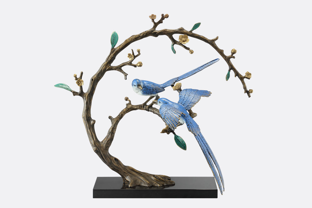 A statue of two blue songbirds perched serenely on a circular branch.