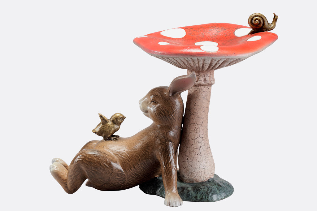 Bunny under a toadstool sculpture with chick and snail - mushroom is birdbath/birdfeeder