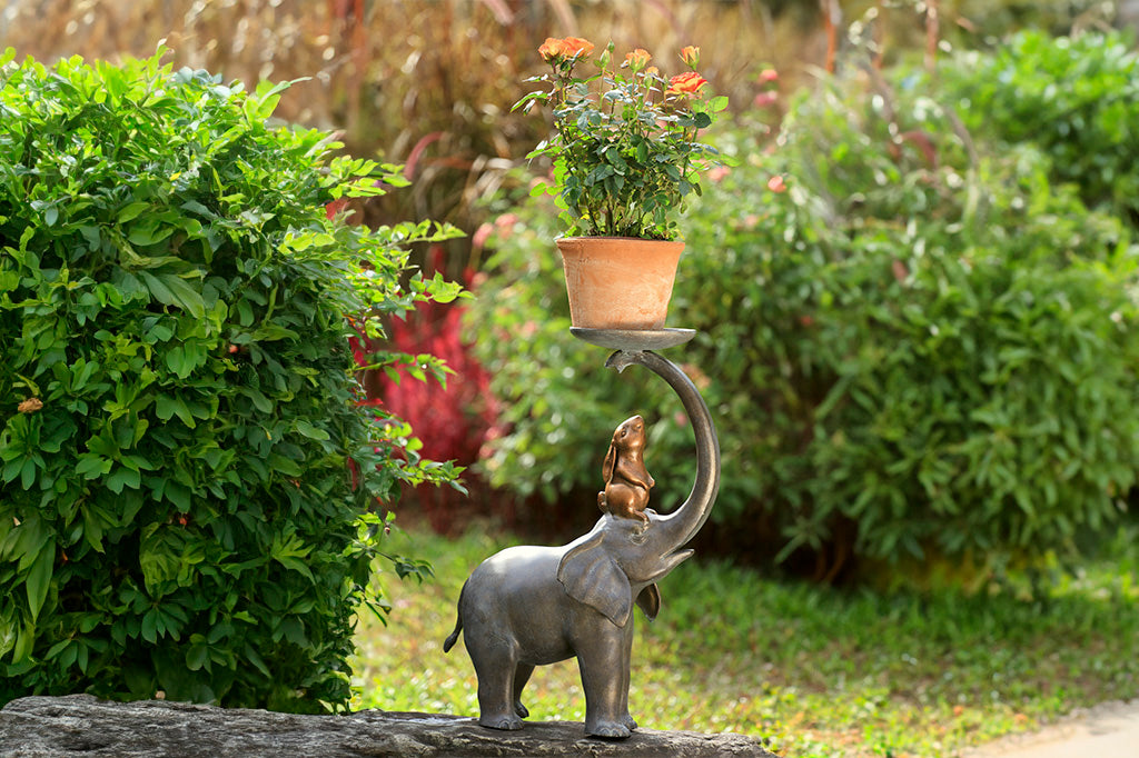 Garden Sculpture Plant Stand shows rabbit sitting on elephant's head, whose trunk holds a plant tray