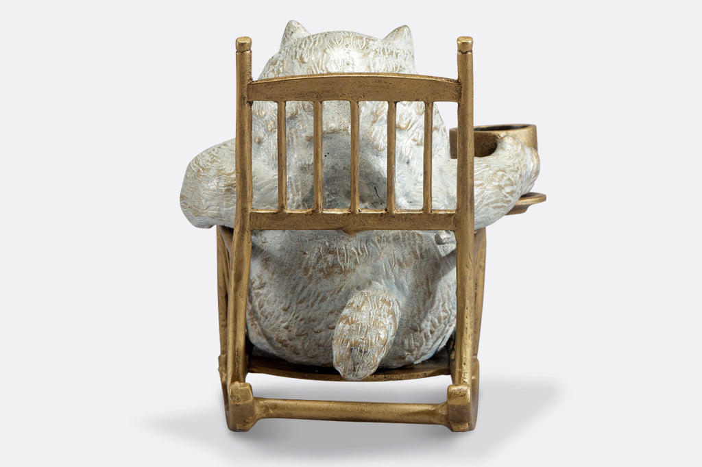 back view of White cat in a rocking chair sculpture. Cat is restfully sitting with eye closes, holding a teacup which could hold LED tealight.