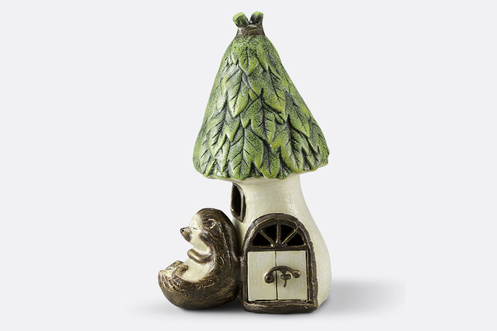 Outdoor Garden candle lantern shows hedgehog sleeping against a woodland house with working door, used to insert votive candle.