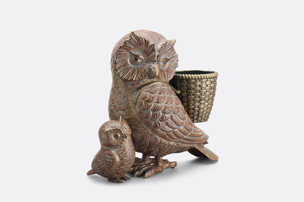 Decorative owl sculpture with a smaller owl and a basket on a white background