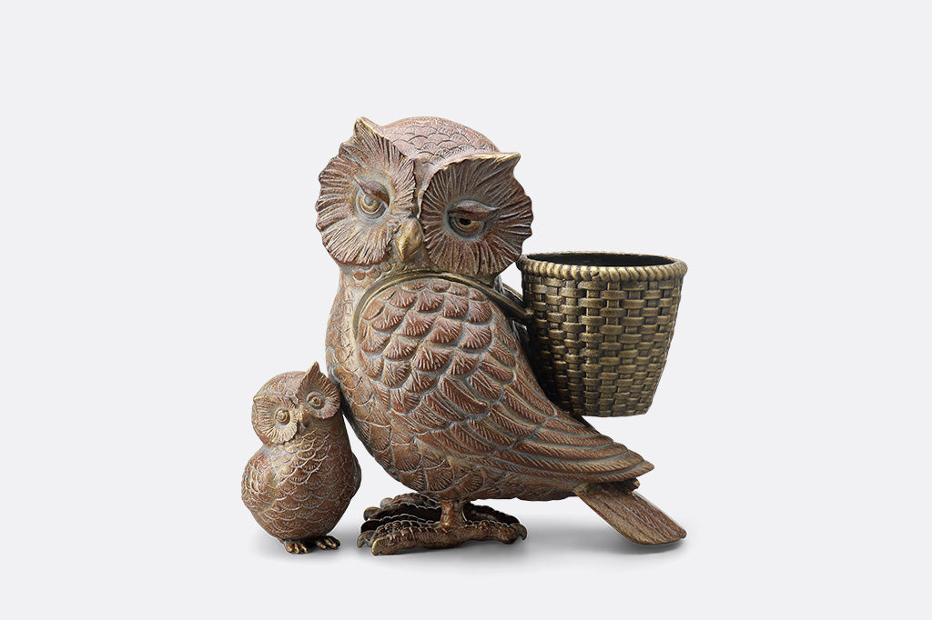 Decorative owl sculpture with a small owl and a basket on a white background