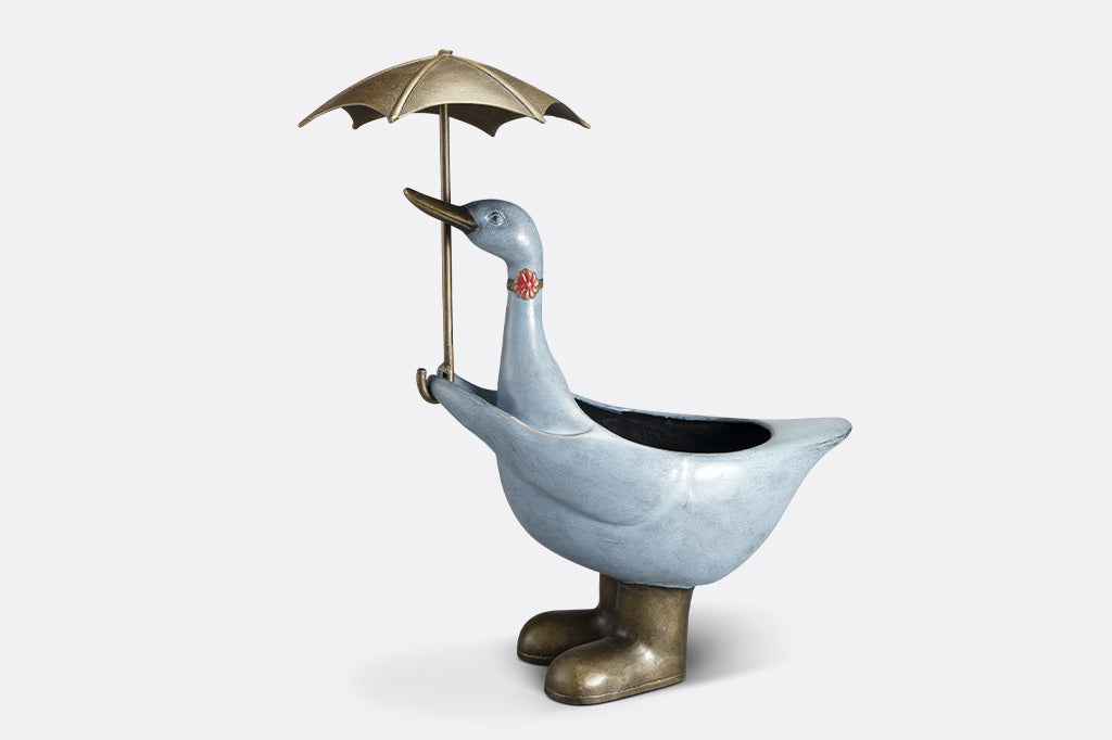 Slate blue goose planter shown holding an umbrella; she wears a flower choker,and rain boots.