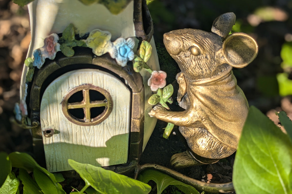 close up view of sculpted mouse and lantern door in garden setting