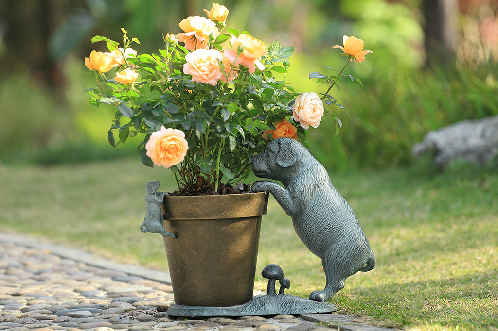 A planter statue with a small puppy holding onto the lip of the pot while a bigger dog peers over.