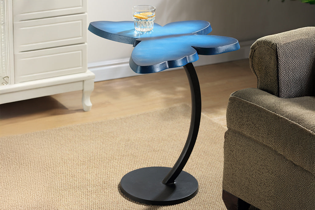 The Butterfly Accent Table in blue has a vibrant blue tabletop shown in a living room with tan furniture. Shown with lemon water in a glass on top.