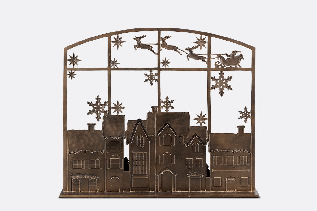 Backside view of decorative metal screen with Christmas design featuring houses, reindeer, and snowflakes 