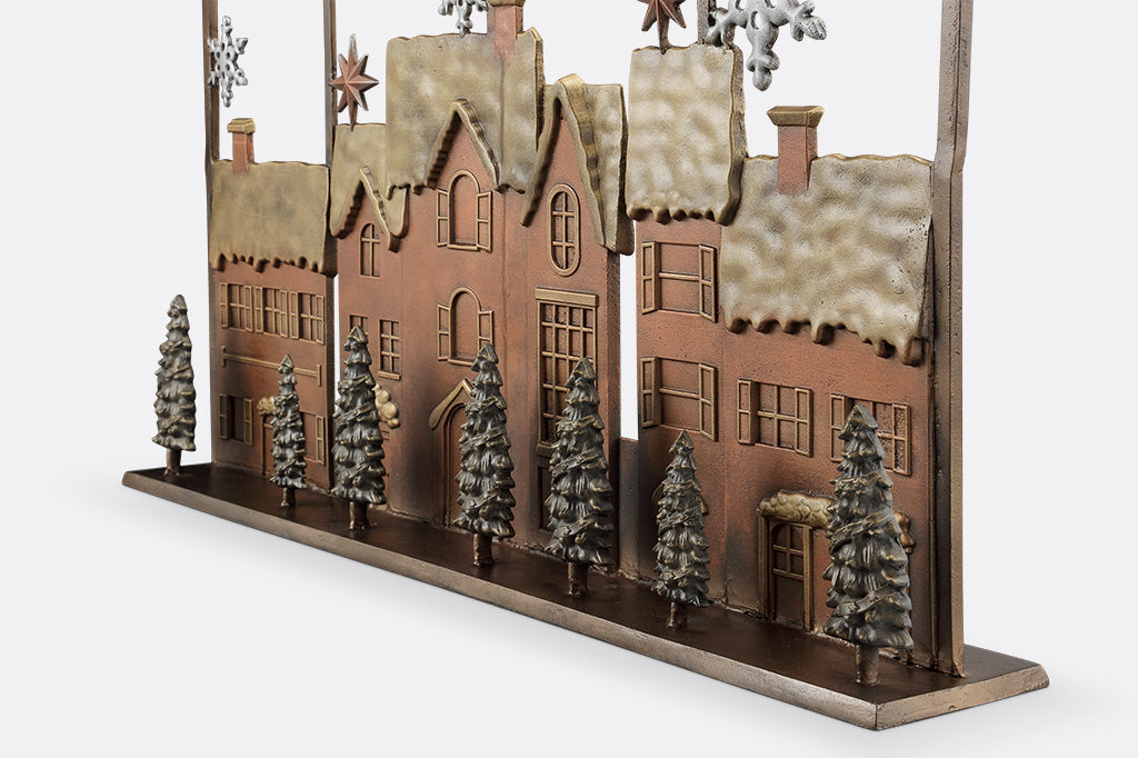 Close up detail view of base of fireplace screen featuring a village scene with houses and trees on a white background