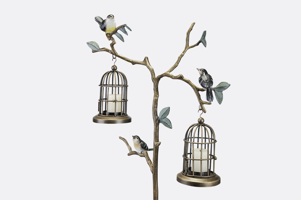 closeup view of a staked garden accent with branch and leaf motif with songbirds. It supports two hanging candle lantern cages.