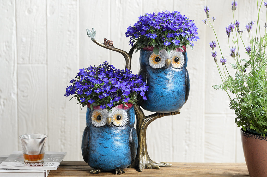blue owl cast metal planter with flowering plants inside set on counter 