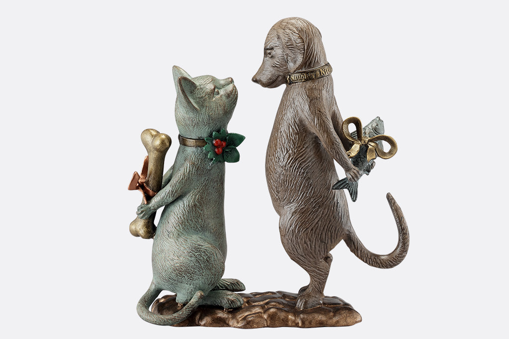 Statue of a cat holding a bone and a dog holding a fish on a white background.