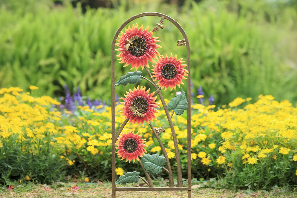 cast metal red sunflower and bees garden trellis set in garden bed