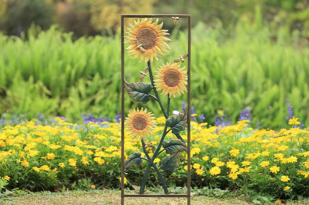 cast metal sunflower and bee trellis set in garden bed 