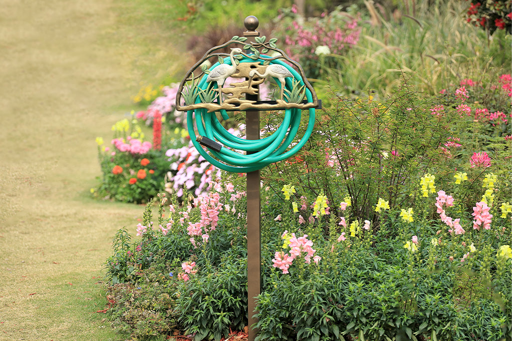 heron staked hose holder in garden bed 