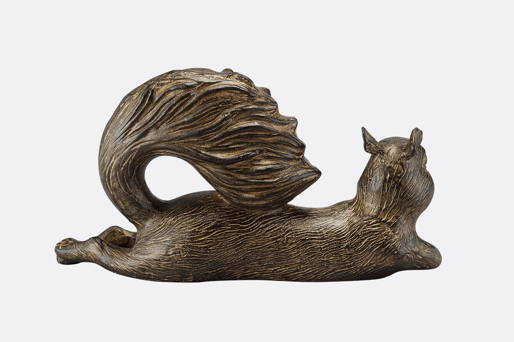 The back of a squirrel statue leaning on it's side with it's tail up.