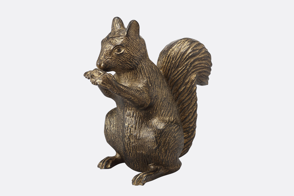 A side profile of a statue of a squirrel nibbling and holding a little acorn in it's paws.