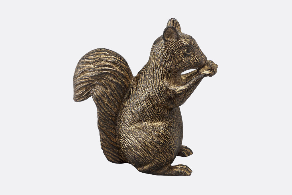 A side profile of a statue of a squirrel nibbling and holding a little acorn in it's paws.