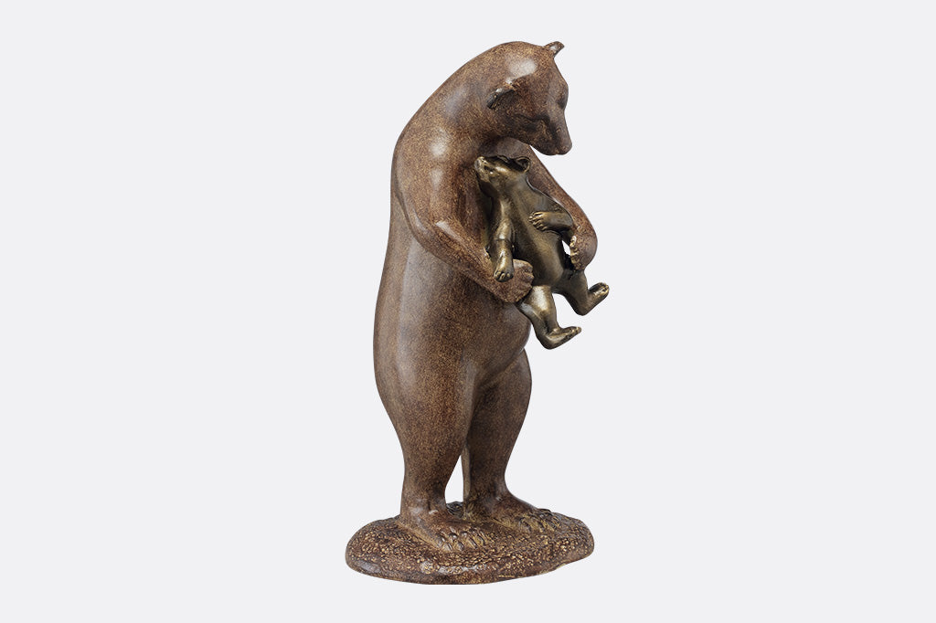 The side profile of a brown sculpture of a bear holding a cub to hug them.