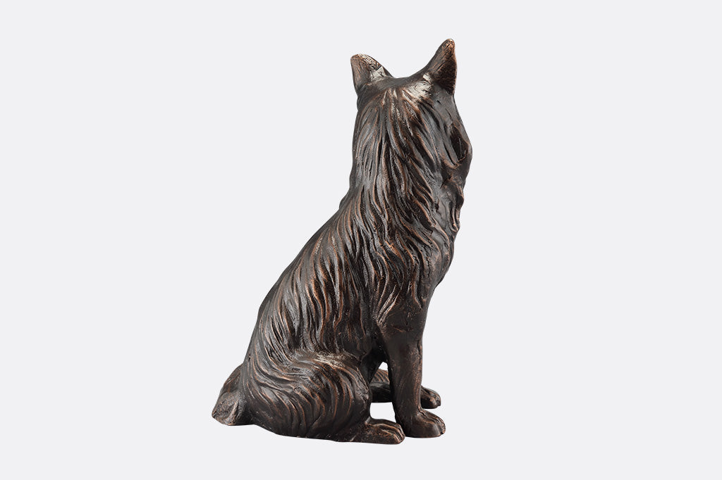 The back of a brown sculpture of a fox sitting.